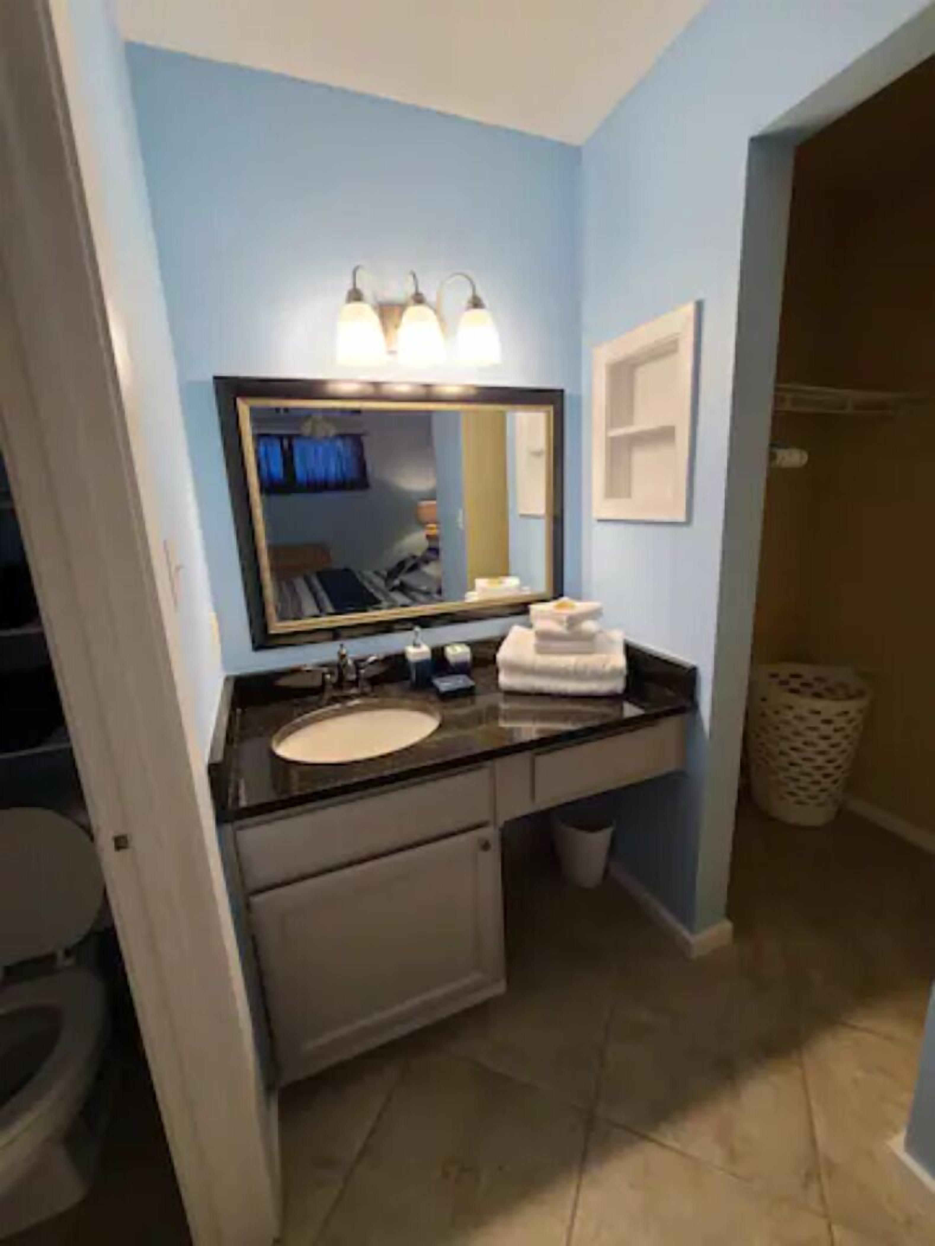 A bathroom with a sink, mirror, and towel rack.