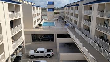 A multi-story hotel with a central pool, balconies, and a parking area.