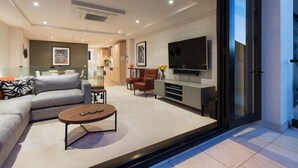 Ein modernes Wohnzimmer mit einer Couch, einem Couchtisch und einem Flachbildfernseher.