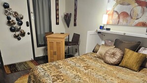 Ein Schlafzimmer mit einem großen Bett, einem Schreibtisch, einem Stuhl und einem Deckenventilator.