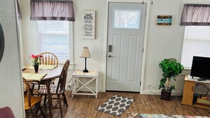 Un comedor acogedor con una mesa y sillas de madera, una mesita auxiliar con una lámpara y una alfombra decorativa.