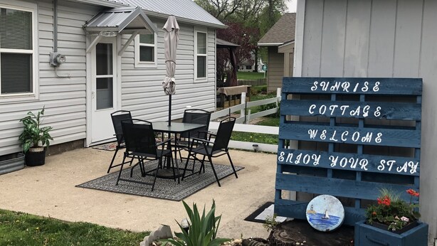 Una cabaña con un patio, un cartel de bienvenida y un cobertizo pequeño.