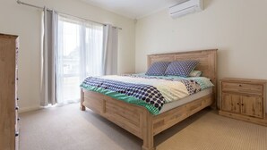 Une chambre à coucher avec un lit en bois, une table de chevet, une armoire et une fenêtre avec des rideaux.