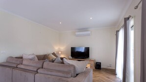 Un salon avec un canapé beige, un téléviseur à écran plat et un plancher en bois.