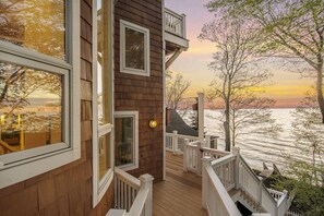 Une terrasse en bois offrant une vue sur une étendue d’eau au coucher du soleil.