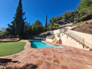 A swimming pool with a stone deck, a patio area with outdoor furniture, and a staircase leading to a covered area. - Villa 'Casa tranquila torrox' with Mountain View, Pool, Garden, Terrace, A/C & Wi-Fi (Competa)
