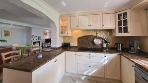 Eine Küche mit weißen Schränken, Granit Arbeitsplatten, einem eingebauten Backofen und einer Kaffeemaschine.
