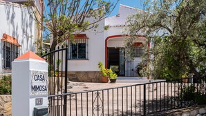 A white building with a red door, a black metal fence, and a mailbox labeled 'CASA MIMOSA 10'. - 'Villa mimosa nationalpark nearby' with Sea & Mountain View, Pool, Garden, Terrace, A/C & Wi-Fi (Cómpeta)