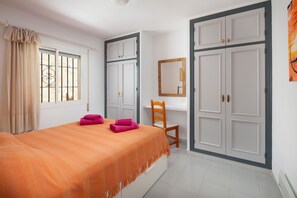 Un dormitorio con cama, escritorio, silla y armario.