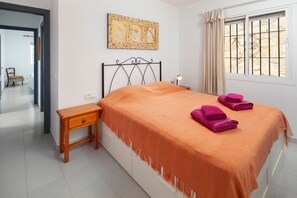 A bedroom with a bed, a nightstand, a chair, a window with bars, and a painting on the wall. - 'Villa mimosa nationalpark nearby' with Sea & Mountain View, Pool, Garden, Terrace, A/C & Wi-Fi (Cómpeta)