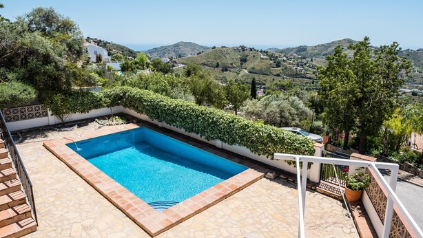 A swimming pool with a view of hills, surrounded by greenery and a white fence. - 'Villa mimosa nationalpark nearby' with Sea & Mountain View, Pool, Garden, Terrace, A/C & Wi-Fi (Cómpeta)