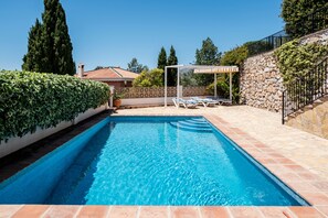 A rectangular swimming pool with a stone border, a pergola with a white canopy, and a stone wall with climbing plants. - 'Villa mimosa nationalpark nearby' with Sea & Mountain View, Pool, Garden, Terrace, A/C & Wi-Fi (Cómpeta)