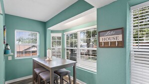 A dining area with a table and two barstools, a sign reading "Lake House", and large windows with blinds. - Fun Summer Lake House w/Firepit located in Ft Worth, Beds 18+, next to Marina  (Fort Worth)