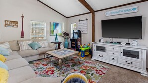A living room with a sofa, coffee table, TV, and a sign that reads "Life is better at the lake." - Fun Summer Lake House w/Firepit located in Ft Worth, Beds 18+, next to Marina  (Fort Worth)