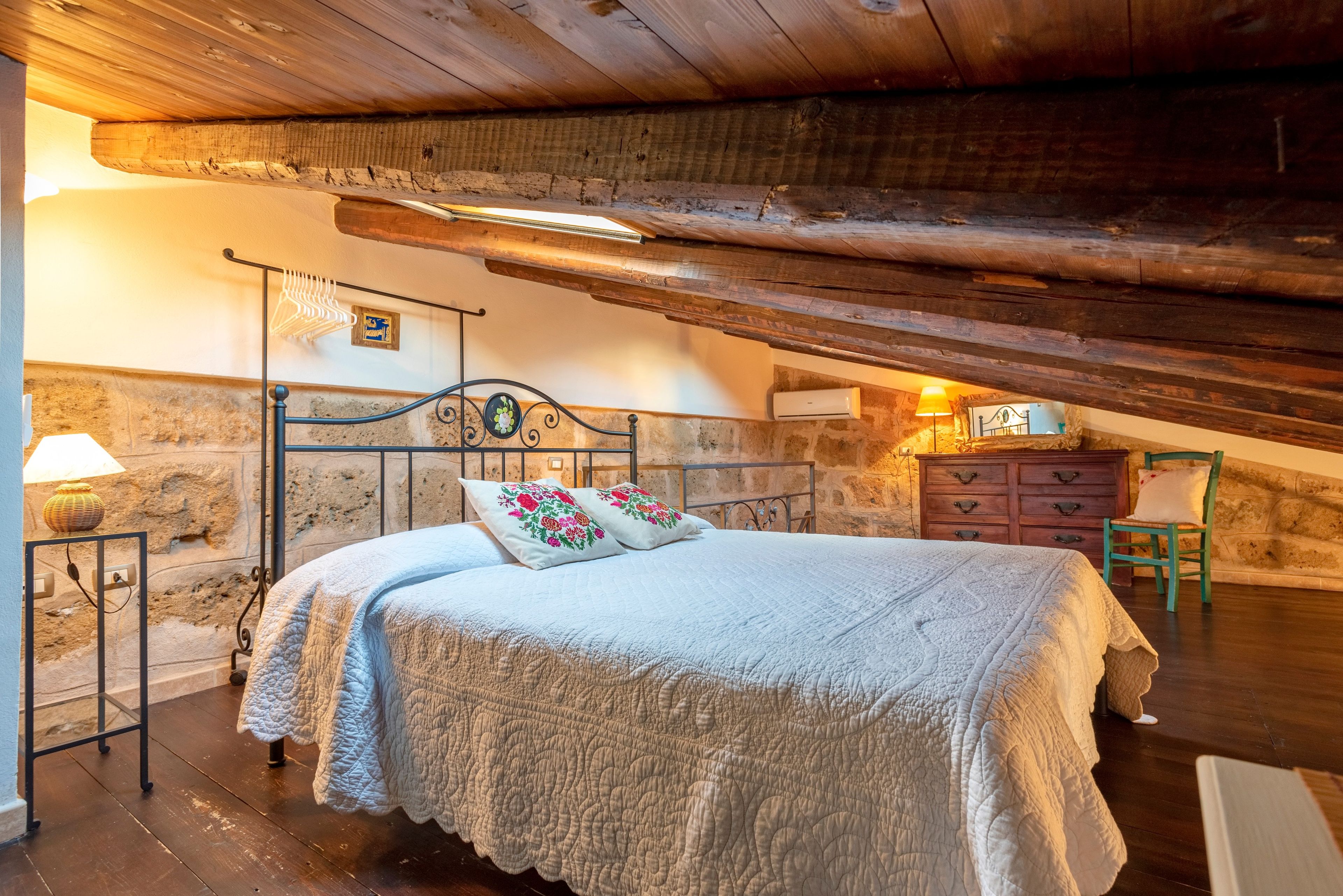 Een gezellig zolderkamer met een bed, een kast en een stoel.