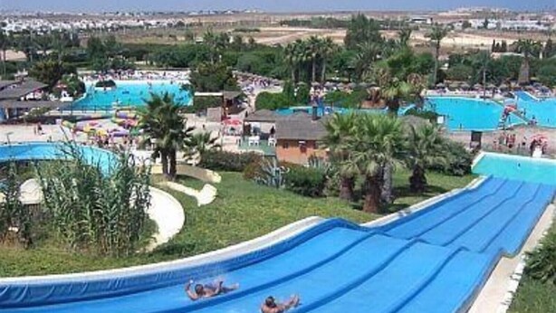 A water slide with multiple lanes, surrounded by pools and palm trees. - Vacation Home "Sophia" with Sea View, Pool, Wi-Fi, Air Conditioning, Terrace & Garden (Torrevieja)