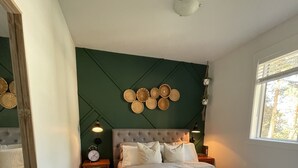 Un dormitorio con una cama grande, un espejo, un reloj en la pared y una lámpara en el techo.