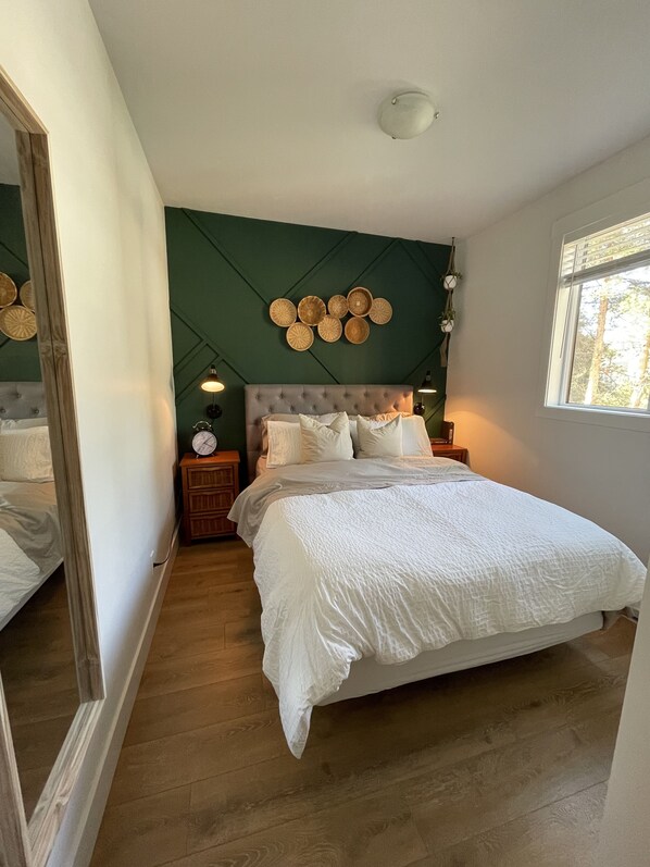 Un dormitorio con una cama grande, un espejo, un reloj en la pared y una lámpara en el techo.