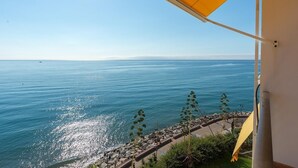 Vista costera con cielo despejado, costa rocosa y un toldo amarillo.