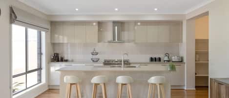 A modern kitchen with a central island, bar stools, and a large window.