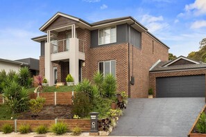 A two-story house with a balcony, brick exterior, and a driveway leading to a garage. - Seagrove Escape - Near the beach & WIFI (Cowes)
