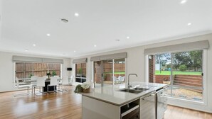 A modern kitchen with a central island, large windows, and a view of the outdoors. - Seagrove Escape - Near the beach & WIFI (Cowes)
