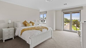 A bedroom with a large bed, a nightstand, a window with a view of the outside, and a ceiling light. - Seagrove Escape - Near the beach & WIFI (Cowes)