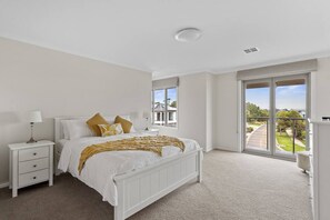 A bedroom with a large bed, a nightstand, a window with a view of the outside, and a ceiling light. - Seagrove Escape - Near the beach & WIFI (Cowes)