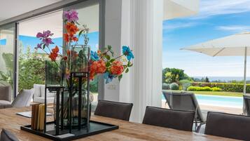 A dining area with a wooden table, chairs, and a glass vase with flowers.