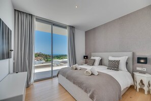 Un dormitorio con una cama grande, una mesita de noche, una lámpara y vistas al exterior.