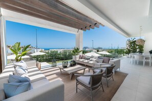 A modern outdoor living area with a sofa, chairs, a table, and umbrellas, overlooking a coastal view. - Villa 'Riva' with Sea Views, Wi-Fi and Air Conditioning (Marbella)