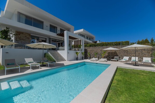A modern house with a swimming pool, outdoor seating, and a stone wall. - Villa 'Riva' with Sea Views, Wi-Fi and Air Conditioning (Marbella)