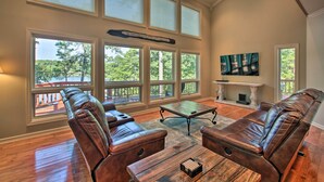 A spacious living room with leather sofas, a wooden coffee table, and large windows offering a view of the outdoors. - Private Dock & Pool Access! Hot Springs Home (Hot Springs)
