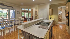 A spacious kitchen with a central island, wooden flooring, and a dining area with chairs and a table. - Private Dock & Pool Access! Hot Springs Home (Hot Springs)