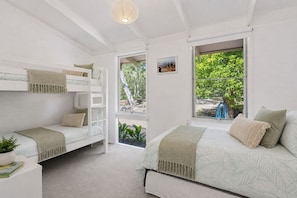 A bedroom with bunk beds, a large window with a view of the outdoors, and a small bedside table with a plant. - Moonah Cottage Rye by Ready Set Stay- Close to the beach & WIFI (Rye)