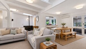 A modern living room with a sofa, a dining table, and a coffee table. - Moonah Cottage Rye by Ready Set Stay- Close to the beach & WIFI (Rye)