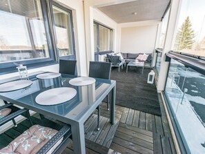 Un balcon avec une table à manger, des chaises et un canapé.