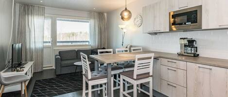 A modern kitchen with a microwave, coffee maker, and a dining area with a table and chairs.