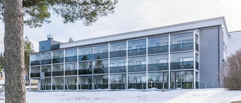 A modern building with large glass windows, a flat roof, and a snow-covered ground.