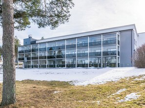 Un bâtiment moderne doté de grandes fenêtres en verre, d’un toit plat et d’un sol recouvert de neige.