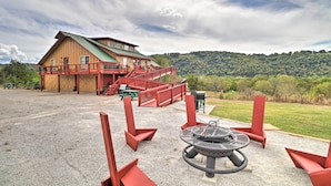 A lodge with a covered deck and a fire pit area.