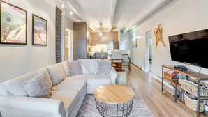 Een moderne woonkamer met een modulaire bank, een houten salontafel en een flatscreen televisie.
