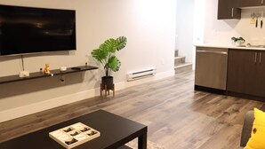 Una sala de estar moderna con un televisor de pantalla plana, una mesa de centro y una planta en maceta.
