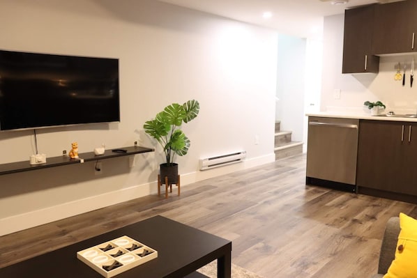 A modern living room with a flat-screen TV, a coffee table, and a potted plant.
