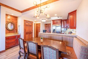 A kitchen with wooden cabinets, a dining table with chairs, and a built-in bench. - Westgate 4409 AB (Park City)