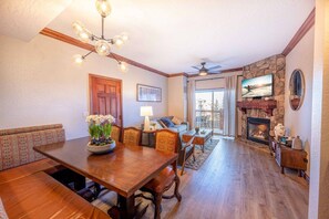 A dining area with a wooden table and chairs, a fireplace, and a television. - Westgate 4409 AB (Park City)