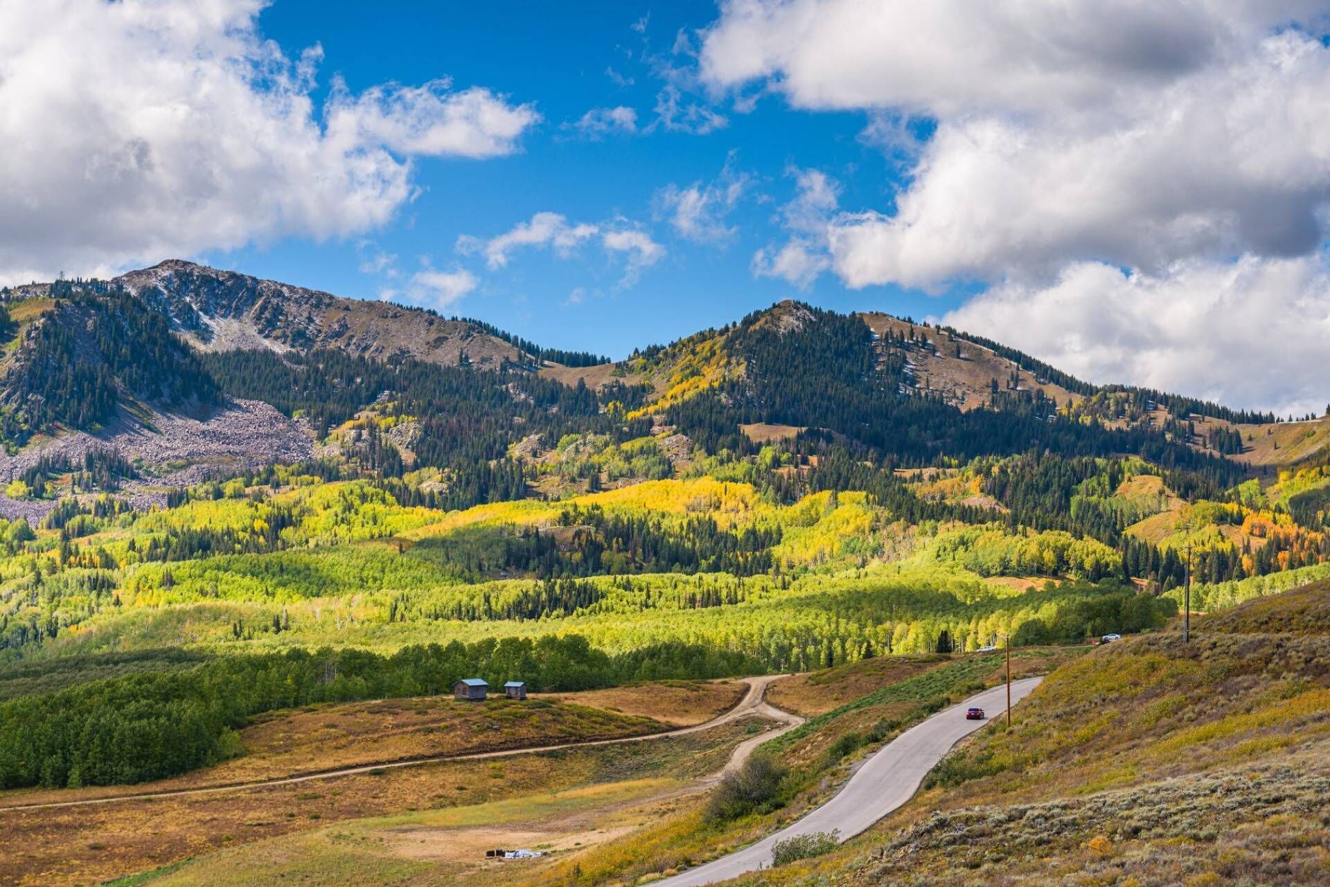 Un paysage montagneux, avec une route sinueuse et des bâtiments dispersés.