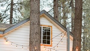 A wooden cabin with a deck, surrounded by trees. - Cabin Near Ski Resort, EV Charge, Kid/Pet Friendly, Fire Pit, Playhouse (Wrightwood)