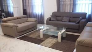 Ein Wohnzimmer mit zwei Sofas, einem Glastisch und einem gemusterten Teppich.