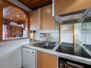 Cozinha moderna com armários de madeira, máquina de lavar louça, fogão e pia.